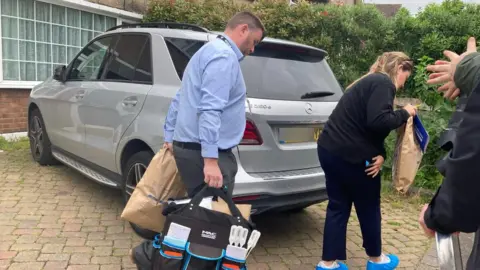 Forensic team walking out of house with bags