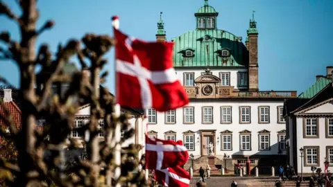 AFP via Getty Images Danish flags flutter in front of Fredensborg Palace in Fredensborg, Denmark, on April 16, 2020