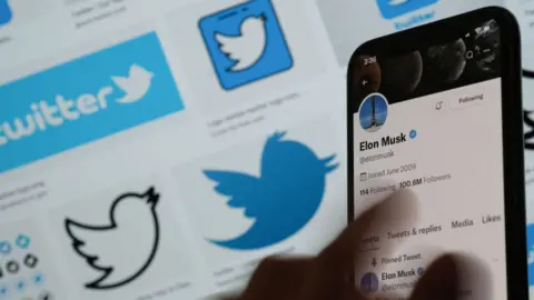 Getty Images Illustration photo of Elon Musk's twitter account on a mobile phone in front of Twitter logos
