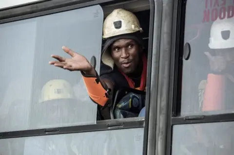 AFP A rescued miner gestures out a bus window carrying some of the hundreds of miners rescued from the Beatrix gold mine shaft number 3 where nearly 1,000 miners were trapped underground following a power outage, in Theunissen on February 2, 2018. Hundreds of gold miners among almost a thousand trapped underground for more than a day in South Africa following a power-cut resurfaced on February 2, mining company Sibanye Gold said, as a rescue effort moved into full swing.