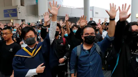 Reuters University students hold their hands in the air