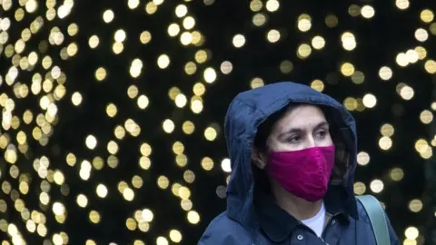 PA Media A woman walking with a face mask on