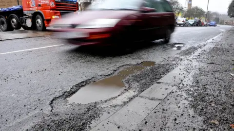 PA Car drives past a pothole