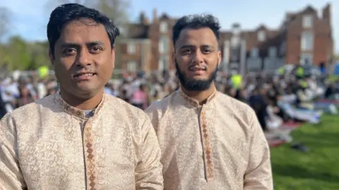 Jon Wright/BBC Two Bangladeshi men in Muslim dress stand in front of crowds outside