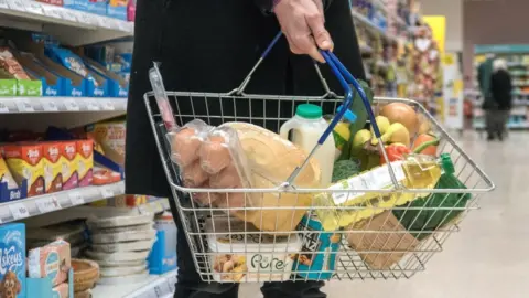 Getty Images Shopper holding a basket full of food