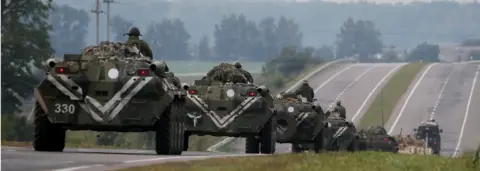 Reuters Armoured Personnel Carriers (APC) ride on the road as smoke rise over a warehouse storing ammunition for multiple rocket launcher systems at a military base in the town of Kalynivka (27 Sept)