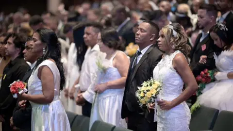 Multiple brides and grooms waiting to get married.