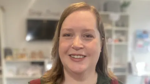 Mousumi Bakshi/BBC Smiling woman with long light brown hair