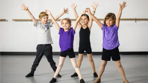 Getty Images Four children in sports kit with their arms in the air