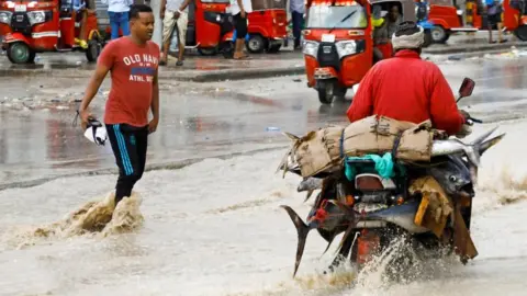 Feisal Omar/Reuters A motorcycle rider carries fish along a flooded street in Mogadishu, Somalia - Friday 28 April 2023