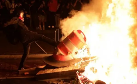 Getty Images A protester kicks an object into a fire near the White House in Washington DC. Photo: 31 May 2020
