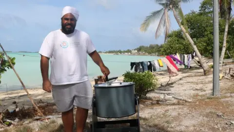 Mr Sawhney with a hand-cranked washing machine on a beach