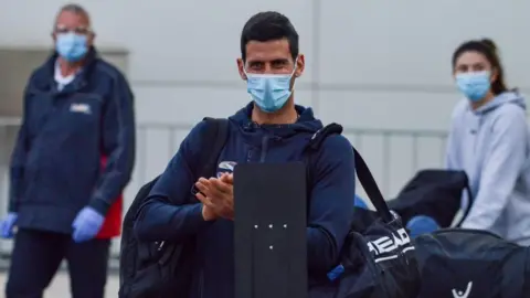 Getty Images Novak Djokovic wearing a mask at Adelaide Airport on his way to hotel quarantine