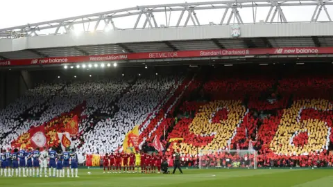 Liverpool and Chelsea players observe a minute's silence on the pitch in front of fans displaying signs that spell out "96"