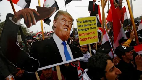 Reuters Supporters of Iraqi Shia cleric Moqtada al-Sadr carry placards depicting Donald Trump