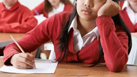 Getty Images Stock image of a student writing with head in hands