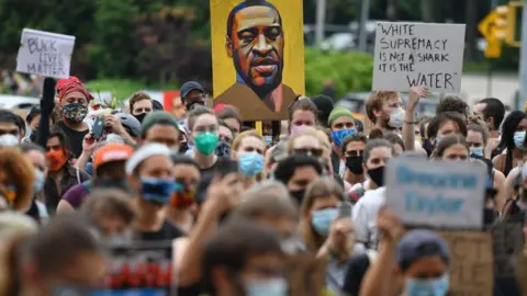 Getty Images Protesters in June hold up a poster of George Floyd, who was killed by police in May