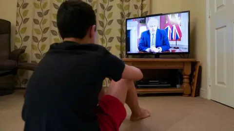 PA Media Family member watching PM on TV