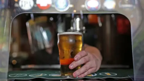 PA Media Man serves pint from behind plastic screen