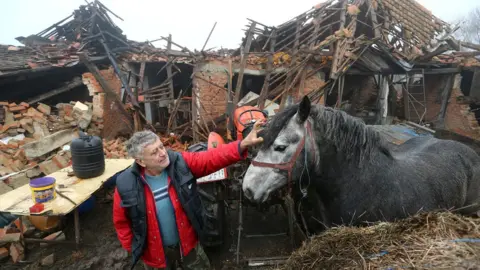 Reuters Farmer Tomislav Suknaic touches his horse in front of his damaged household in Majske Poljan village