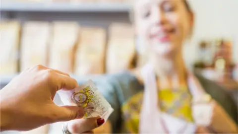 Getty Images Shopkeeper hands over cash