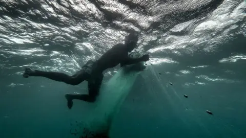 Getty Images Fisherman tends to his net in the sea.