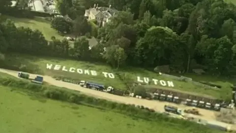 Abbey Desmond Welcome To Luton Sign at Gatwick Airport