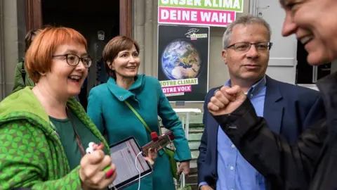 AFP Swiss Green Party president MP Regula Rytz (2nd L) reacts with party members at their meeting place waiting for the first results during the general election in the Swiss capital, Bern.
