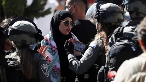 EPA Israeli policewoman talks to a woman next to the Damascus Gate of Jerusalem's Old City (15 June 2021)