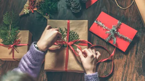 Getty Images Child wrapping presents