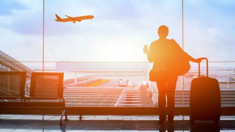 anyaberkut traveller watching a flight take off at n airport departure lounge