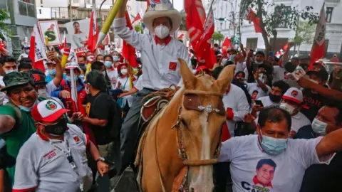 Getty Images Peruvian presidential candidate for the radical leftist party Peru Libre (Free Peru), Pedro Castillo, rides a horse holding a giant pencil during the closing rally of his campaign in Lima on April 8, 2021
