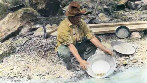 Getty Images A prospector pans for gold in northern California. Hand tinted photograph, circa 1890.