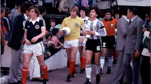 Getty Images 1979 International Football Friendly.Scotland v Argentina.Kenny Dalglish leads out the Scotland team followed by Alan Rough and George Burley.Daniel Passarella leads out the Argentine team.(Photo by Mark Leech/Getty Images)