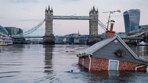 Getty Images A replica of a British house floats in front of Tower Bridge on the river Thames