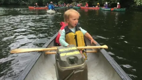 Family photo Kiara wearing a life-jacket in a canoe on the water
