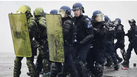 AFP / Getty Images Riot police carry shields covered in yellow paint during protests in Paris on 1 December 2018