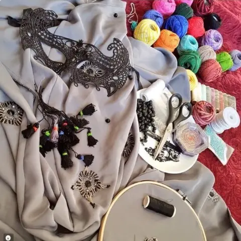 Ana_iba2/Twitter Abaya and veil-mask alongside multi-coloured thread and sewing equipment