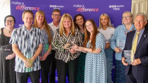 BBC A large group of men and women holding glass trophies