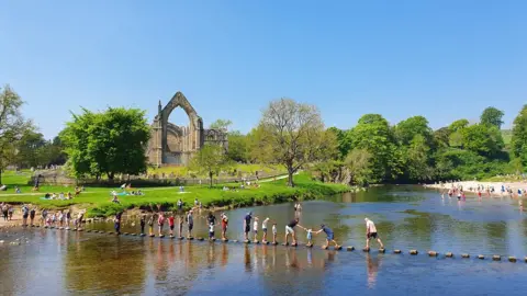 PA Media People enjoy the sunshine at Bolton Abbey in Yorkshire on Bank Holiday Monday