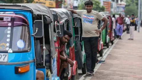 EPA-EFE/REX/Shutterstock Auto rickshaws queue to fetch fuel from a gas station amid a fuel shortage in Colombo, Sri Lanka, 17 June 2022.