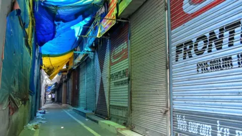 Getty Images A man walks past closed shops during a shutdown in Srinagar, Kashmir.