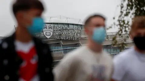 Reuters Students wearing masks walk past a Northumbria University building