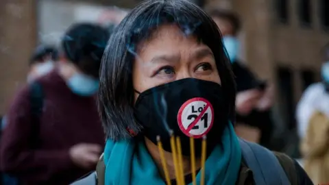 Getty Images May Chiu lights incense during a vigil following a demonstration against anti-Asian racism in Montreal, Quebec, Canada, on March 21, 2021.