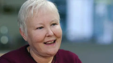 Woman with short, grey hair smiling.