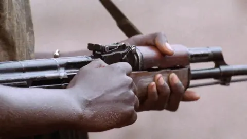 Hands holding the barrel of a rifle.