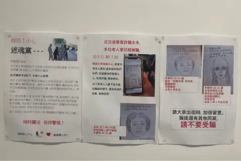 Printed posters tacked onto a wall, warning about the blessing scam with sketches of suspects.