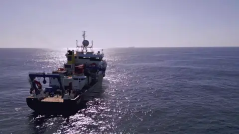 National Oceanography Centre Royal Research Ship Discovery in the Atlantic heading towards the sun and the horizon.