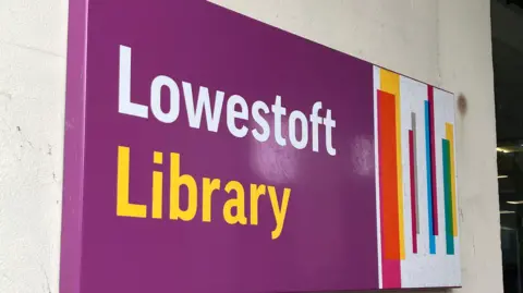 Guy Campbell/BBC A purple sign with yellow and white lettering reading Lowestoft Library