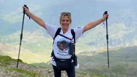 Clair Todd  Clair Todd at the top of Snowdonia with poles in the air 